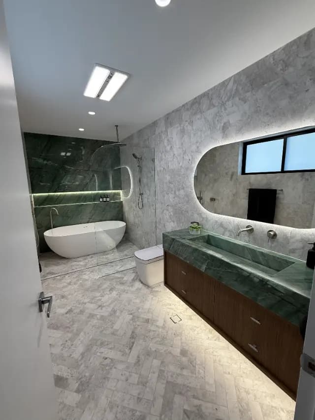 Completed bathroom with green stone vanity and herringbone floor